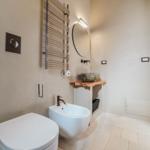 Badezimmer mit Toilette, Bidet und Steinwaschbecken auf Holzunterschrank