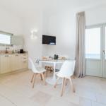 Küche mit Esstisch, TV und Balkontür.