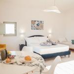 Schlafzimmer mit Bett, Sitzbank und Esstisch mit Frühstück.