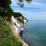Steilküste mit grüner Vegetation und blauem Meer unter klarem Himmel.