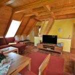 Wohnraum mit Holzdecke, Sofa, Fernseher und Essbereich.