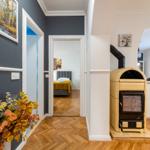 Haus mit Holzfußboden, Kaminofen und Blick in Schlafzimmer und Wohnbereich.