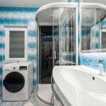 Badezimmer mit Dusche, Waschmaschine und Waschtisch