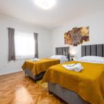 Zwei Betten mit gelben Decken, Holzboden und Wandbild