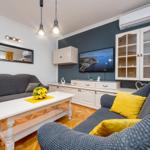 Wohnzimmer mit grauem Sofa, weißem Tisch und Fernseher an der Wand.