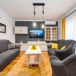 Wohnzimmer mit grauen Sofas, weißem Tisch und Holzboden