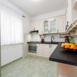 Küche mit weißen Schränken, schwarzer Arbeitsplatte und Kühlschrank mit Wasserspender.