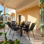 Terrasse mit Tisch und Stühlen, Pflanzen und Blick auf Hauswand.