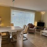 Wohn- und Essbereich mit Sofa, Fernseher und Essplatz.