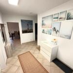 Flur mit Wandbildern, Schrank und Teppich. Durchgang zur Küche.