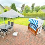 Terrasse mit Tisch, Stühlen, Sonnenschirm und Strandkorb.