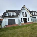 Moderne Villa mit Garage und Garten. Eingangstür und Fenster sichtbar.