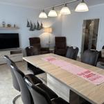 Esszimmer mit Esstisch, Stühlen und Fernseher. Wanddekoration und Beleuchtung.