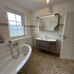 Badezimmer mit Badewanne, Waschbecken und Spiegel