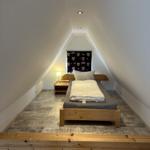 Schlafzimmer mit Dachschrägen, Bett und Nachttisch.