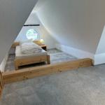 Schlafzimmer mit Holzbett und runden Fenster unter Dachschräge