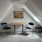 Dachgeschosszimmer mit Tisch, zwei Stühlen und Wandbild