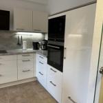 Moderne Küche mit weißen Schränken und integriertem Ofen.