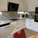 Moderne Küche mit weißen Schränken und Edelstahlgeräten.