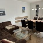 Wohn- und Essbereich mit Sofa, Tisch und Stühlen sowie Wandbildern.