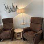 Zwei braune Sessel, Tisch und Stehlampe im Wohnbereich.