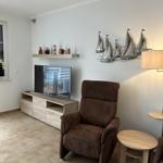 Wohnzimmer mit braunem Sessel, Fernseher und Wanddekoration mit Schiffen.