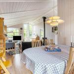 Dining room with wooden table, chairs, and tablecloth. Background shows living area with fireplace and windows.