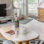 Living room with wooden floor, TV, coffee table, and flowers.