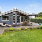 A gray house with a terrace, garden, and sun loungers.