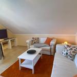 Wohnzimmer mit Sofa, Couchtisch und Fernseher unter Dachschräge