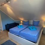 Schlafzimmer mit Doppelbett, Nachttischen und Sofa unter schräger Decke.