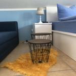 Schlafzimmer mit Bett, Sofa, Nachttisch und zwei Tischen auf Fellteppich.