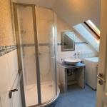 Badezimmer mit Dusche, Waschbecken und Waschmaschine unter Dachschräge