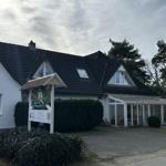 House with gabled roof, conservatory, and sign at entrance.