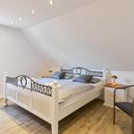 Schlafzimmer mit Dachschrägen, Bett, Nachttisch und Stuhl.