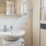 Badezimmer mit Waschbecken, Spiegel und Duschvorhang.