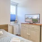 Schlafzimmer mit Bett, Fernseher und Fenster.