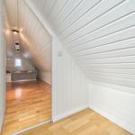 Schlafzimmer mit Dachschrägen, Holzboden und Bett unter Dach