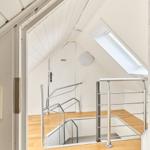 Dachgeschoss mit Treppe und Dachfenster. Holzboden und weiße Wände.