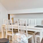 Esszimmer mit weißem Tisch und Stühlen, Holzwand und Deckenbalken