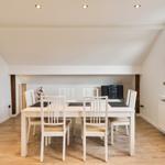 Esszimmer mit weißem Tisch und Stühlen, Holzboden und Fenster mit Blick.