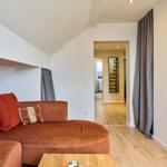 Wohnzimmer mit braunem Sofa, Holzboden und Blick in den Flur.