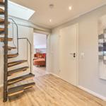 Haus mit Wendeltreppe, Holzboden und Wandbild. Durchgang zum Wohnzimmer mit Sofa.