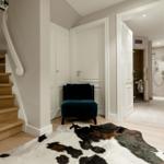 Hausflur mit Treppenhaus, Sitzgelegenheit und Blick in die Dusche.