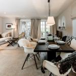 Wohn- und Essbereich mit Tisch, Stühlen, Sofa und Fenstern.