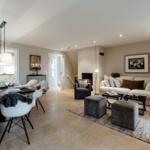 Wohn- und Essbereich mit Sofa, Stühlen und Esstisch. Fliesenboden und Wandbild.