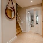 Eingangsbereich mit Holztreppe und runden Spiegel an der Wand.