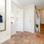Eingangsbereich mit Spiegel, Garderobe und Holztreppe.