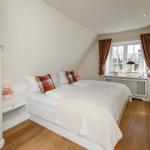 Schlafzimmer mit Dachschräge, Bett, Fenster und Holzboden.