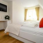 Schlafzimmer mit Bett, Fenster, TV und Schreibtisch.